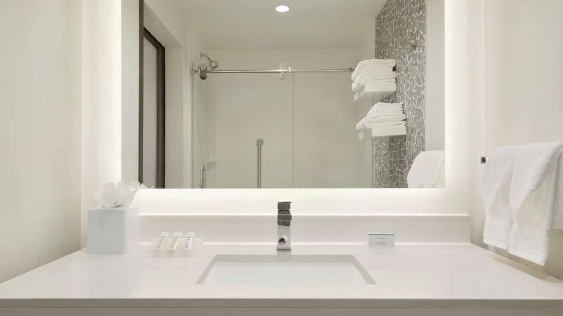 Modern guest bathroom with illuminated vanity, walk-in shower and contemporary finishes at Hilton Garden Inn Calgary Downtown.