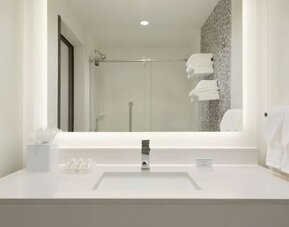 Modern guest bathroom with illuminated vanity, walk-in shower and contemporary finishes at Hilton Garden Inn Calgary Downtown.
