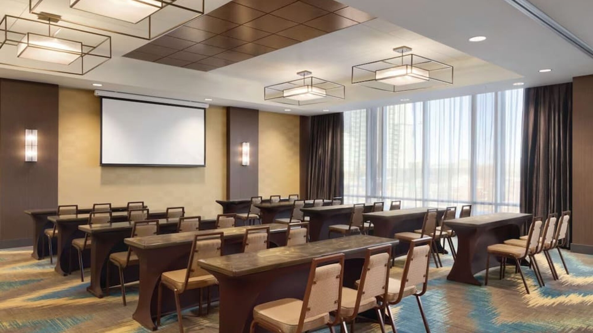 Modern meeting room with classroom-style seating and presentation screen at Hilton Garden Inn Calgary Downtown.