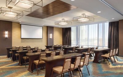Modern meeting room with classroom-style seating and presentation screen at Hilton Garden Inn Calgary Downtown.