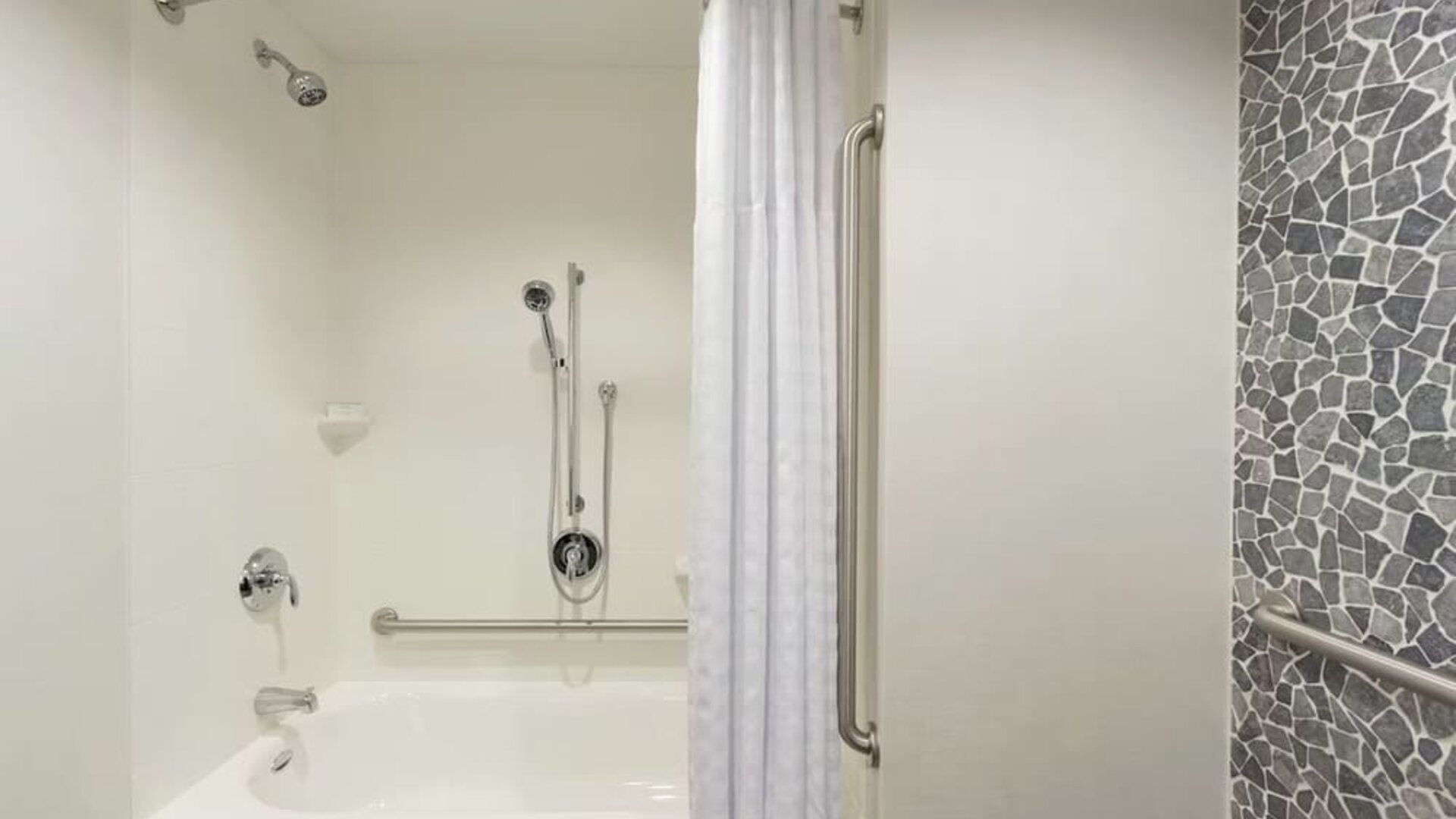 Accessible guest bathroom with grab bars, bathtub and shower combination at Hilton Garden Inn Calgary Downtown.