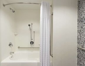 Accessible guest bathroom with grab bars, bathtub and shower combination at Hilton Garden Inn Calgary Downtown.