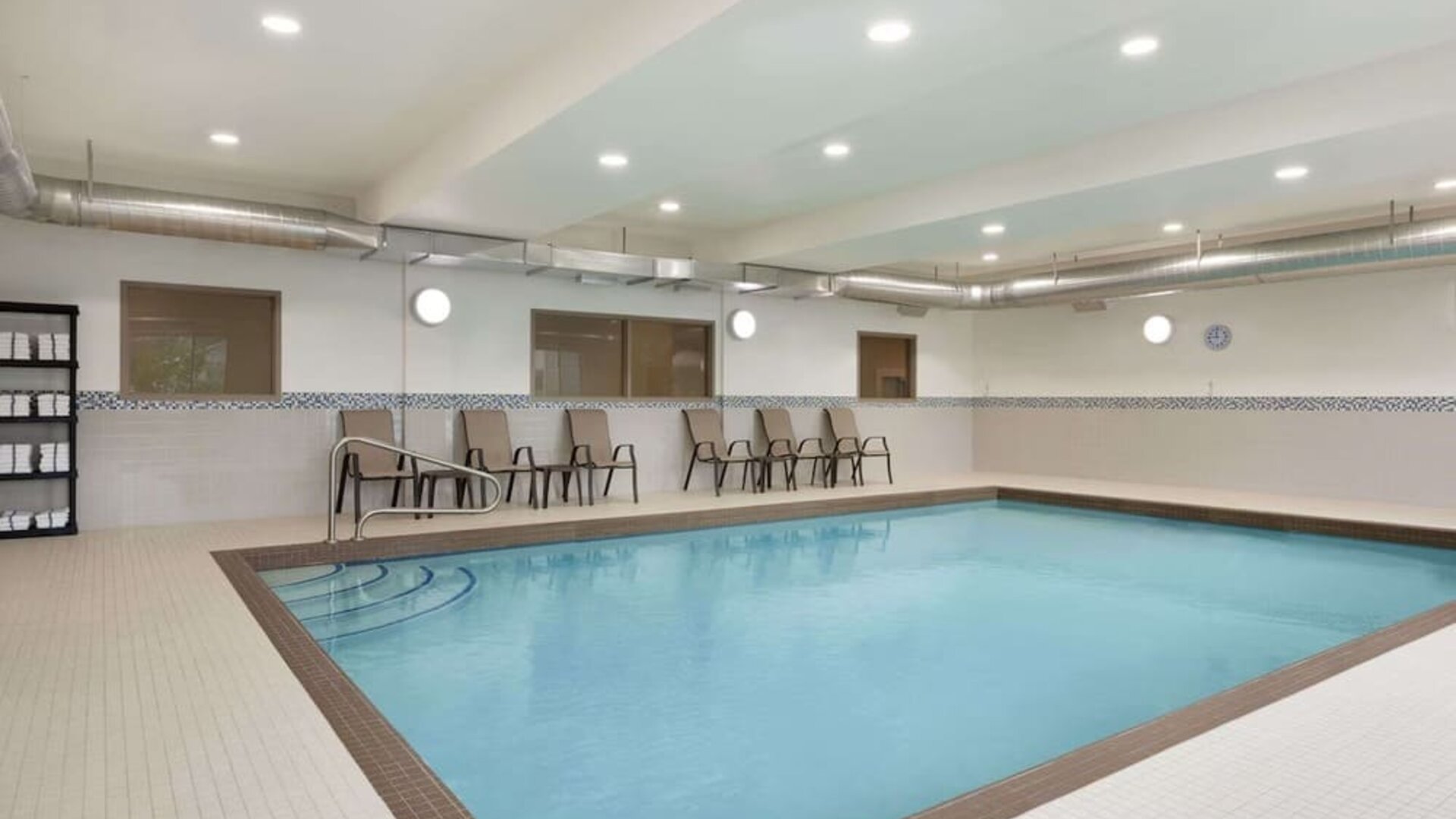 Spacious indoor swimming pool with easy-entry steps and poolside seating at Days Inn & Suites By Wyndham Lindsay.