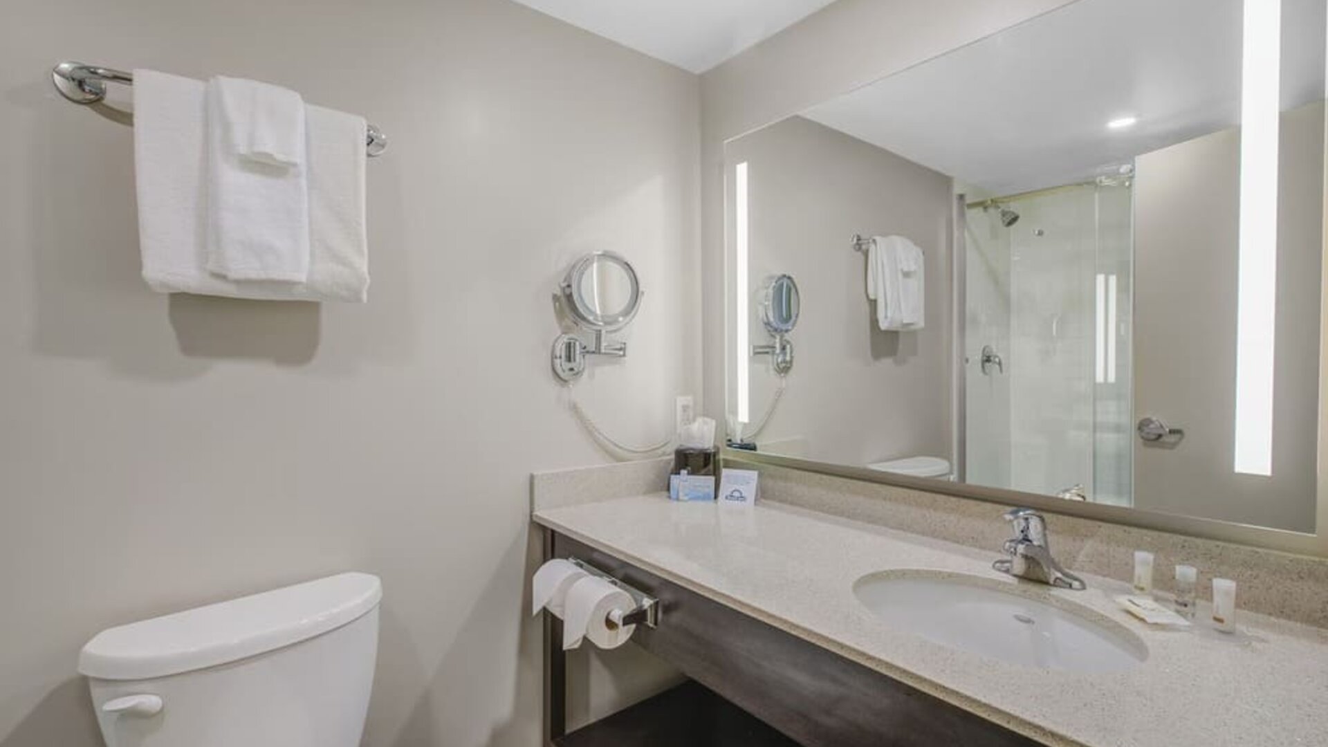 Modern guest bathroom with illuminated vanity, walk-in shower and complimentary toiletries at Days Inn & Suites By Wyndham Lindsay.