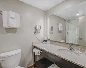 Modern guest bathroom with illuminated vanity, walk-in shower and complimentary toiletries at Days Inn & Suites By Wyndham Lindsay.