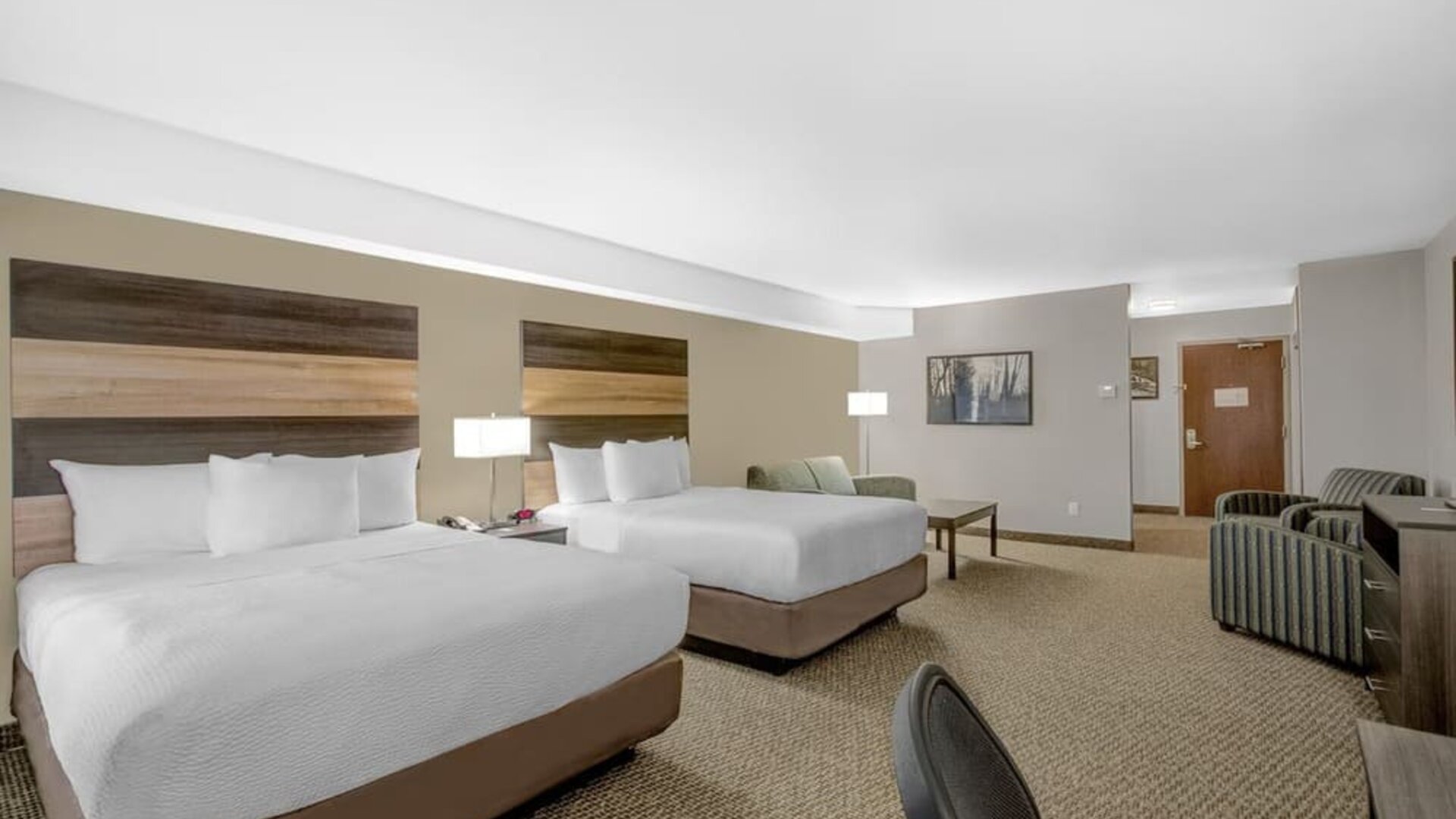 Spacious guest room with two queen beds, comfortable seating area and modern amenities at Days Inn & Suites By Wyndham Lindsay.