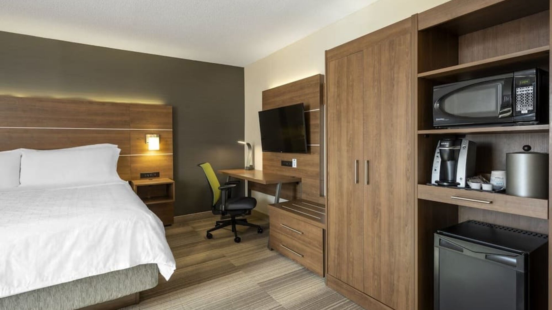 Modern king guest room featuring a work desk, mini fridge, microwave, coffee maker and flat-screen TV at Holiday Inn Express Toronto Downtown.