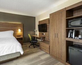 Modern king guest room featuring a work desk, mini fridge, microwave, coffee maker and flat-screen TV at Holiday Inn Express Toronto Downtown.