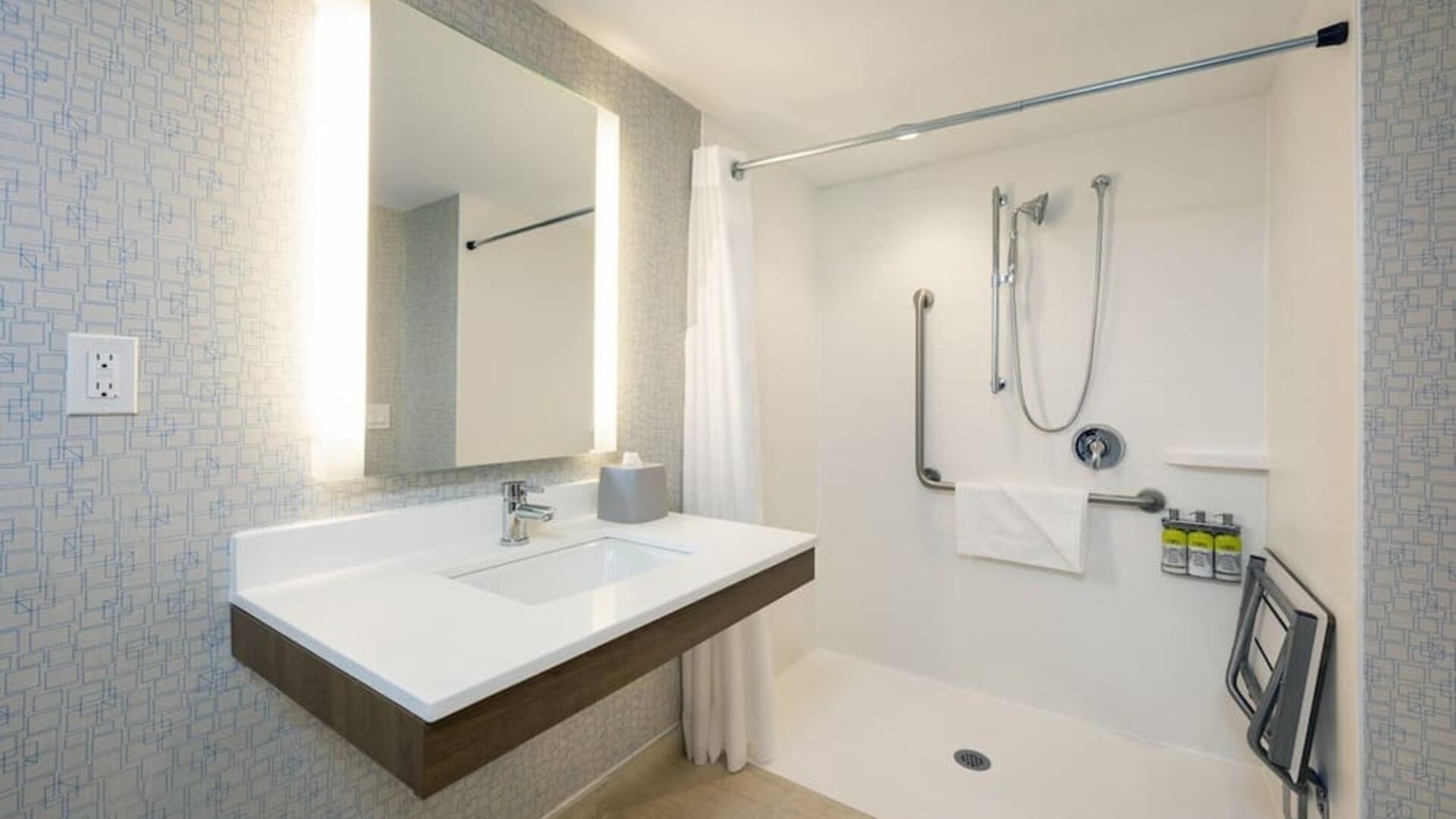 Accessible guest bathroom with roll-in shower, grab bars and modern vanity at Holiday Inn Express Toronto Downtown.