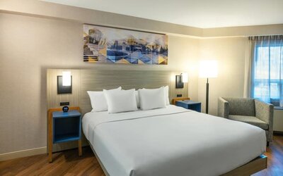 Inviting king bed with premium linens, bedside lighting, and cozy armchair for a relaxing stay at Comfort Inn Amherst.