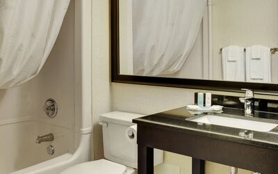 Modern guest bathroom featuring a shower and tub combination, spacious vanity, fresh towels, and complimentary bath amenities at Comfort Inn Thetford Mines.