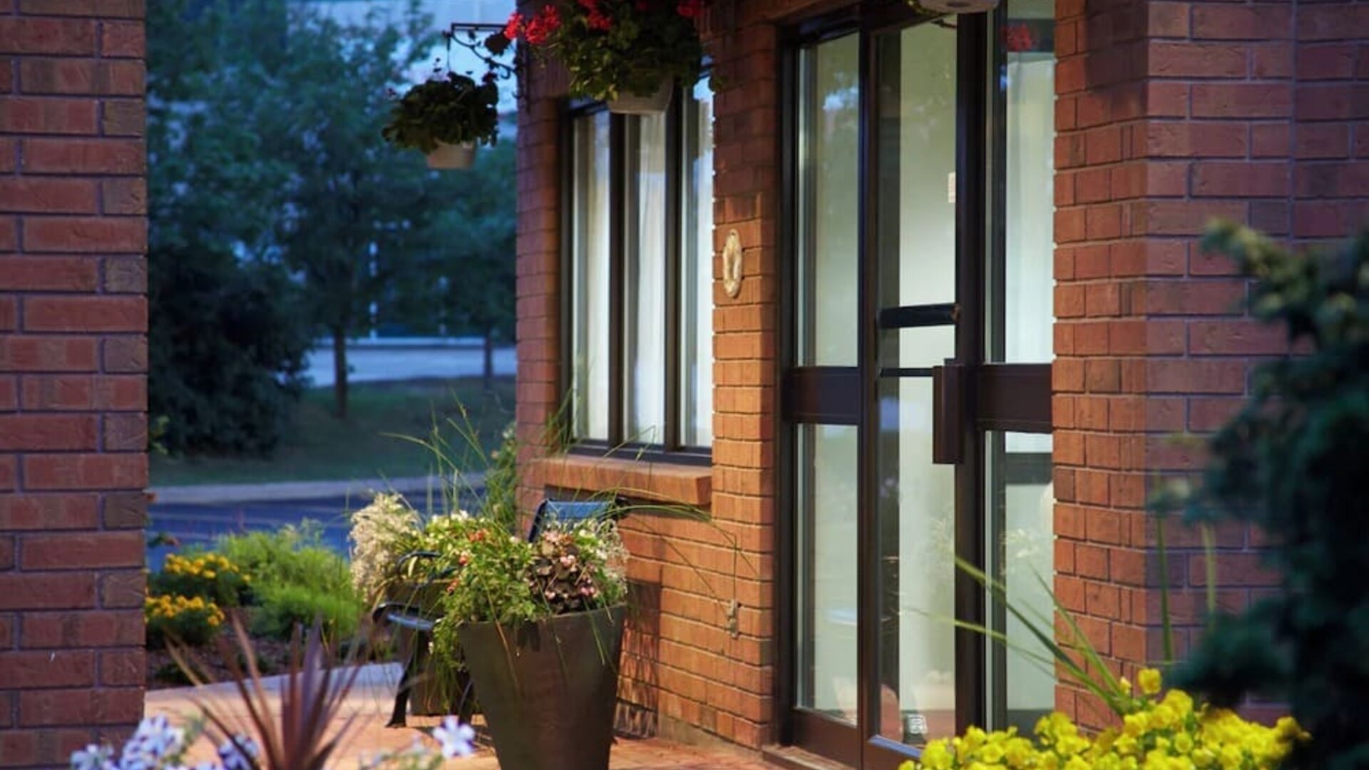 Welcoming hotel entrance surrounded by landscaped gardens and colorful seasonal flowers at Comfort Inn Thetford Mines.