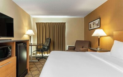 Spacious king guest room featuring premium bedding, microwave, mini fridge, work desk, and comfortable seating at Comfort Inn Thetford Mines.