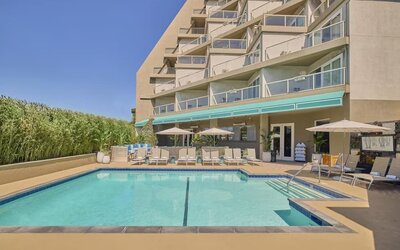 Outdoor swimming pool surrounded by lounge chairs, shaded seating, and relaxing spaces to enjoy the California sunshine at Hyatt Centric Delfina Santa Monica.