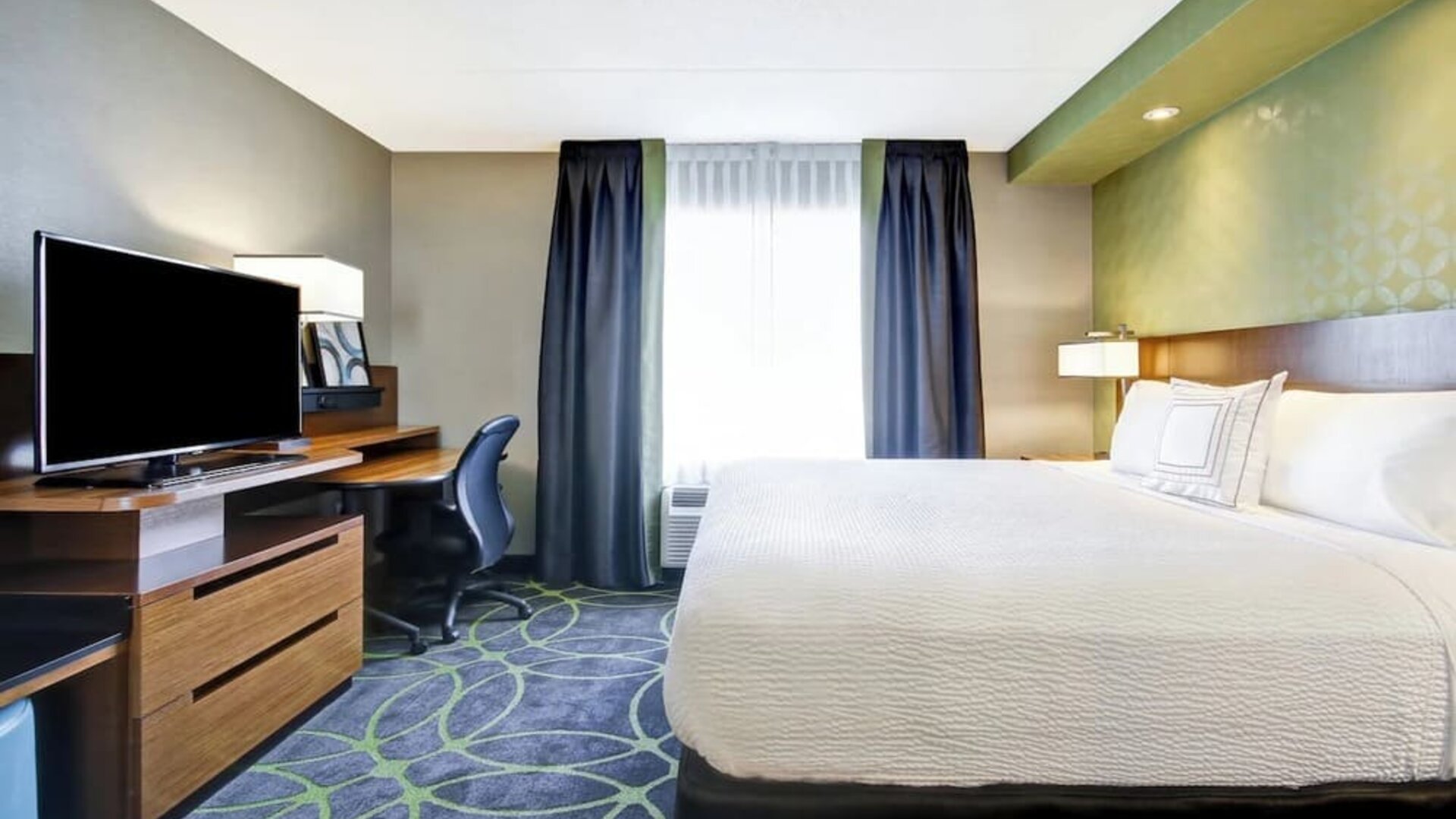 Contemporary king guest room with a work desk, flat-screen TV, and comfortable bedding at Fairfield Inn & Suites Guelph.