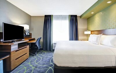 Contemporary king guest room with a work desk, flat-screen TV, and comfortable bedding at Fairfield Inn & Suites Guelph.