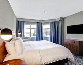 Bright king guest room with large windows, modern furnishings, and city views at Four Points by Sheraton St. Catharines Niagara Suites.