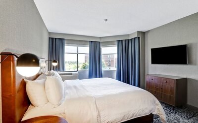 Bright king guest room with large windows, modern furnishings, and city views at Four Points by Sheraton St. Catharines Niagara Suites.