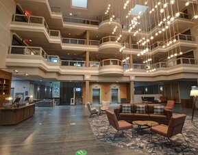 Contemporary atrium lobby with stylish seating, open architecture, and modern lighting at Four Points by Sheraton St. Catharines Niagara Suites.