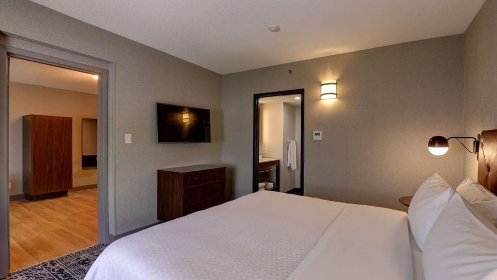 Spacious suite featuring a king bed, separate living area, and modern furnishings at Four Points by Sheraton St. Catharines Niagara Suites.