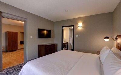 Spacious suite featuring a king bed, separate living area, and modern furnishings at Four Points by Sheraton St. Catharines Niagara Suites.
