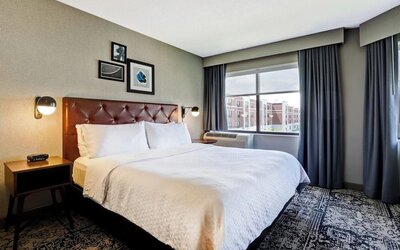 Contemporary king guest room featuring plush bedding, large windows, and modern décor at Four Points by Sheraton St. Catharines Niagara Suites.