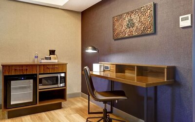 Functional in-room workspace with ergonomic desk, mini refrigerator, microwave, and coffee station at Four Points by Sheraton St. Catharines Niagara Suites.