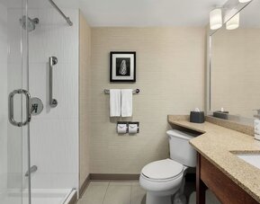 Modern guest bathroom featuring a glass-enclosed walk-in shower, spacious vanity, and premium bath amenities at Holiday Inn Oakville Centre.