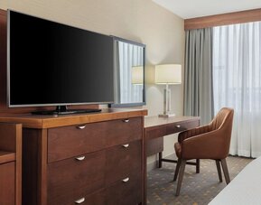 In-room workspace with writing desk, flat-screen TV, and functional storage designed for business and leisure travelers at Holiday Inn Oakville Centre.