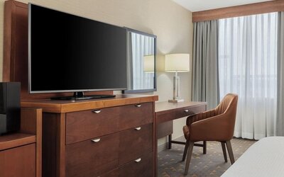 In-room workspace with writing desk, flat-screen TV, and functional storage designed for business and leisure travelers at Holiday Inn Oakville Centre.