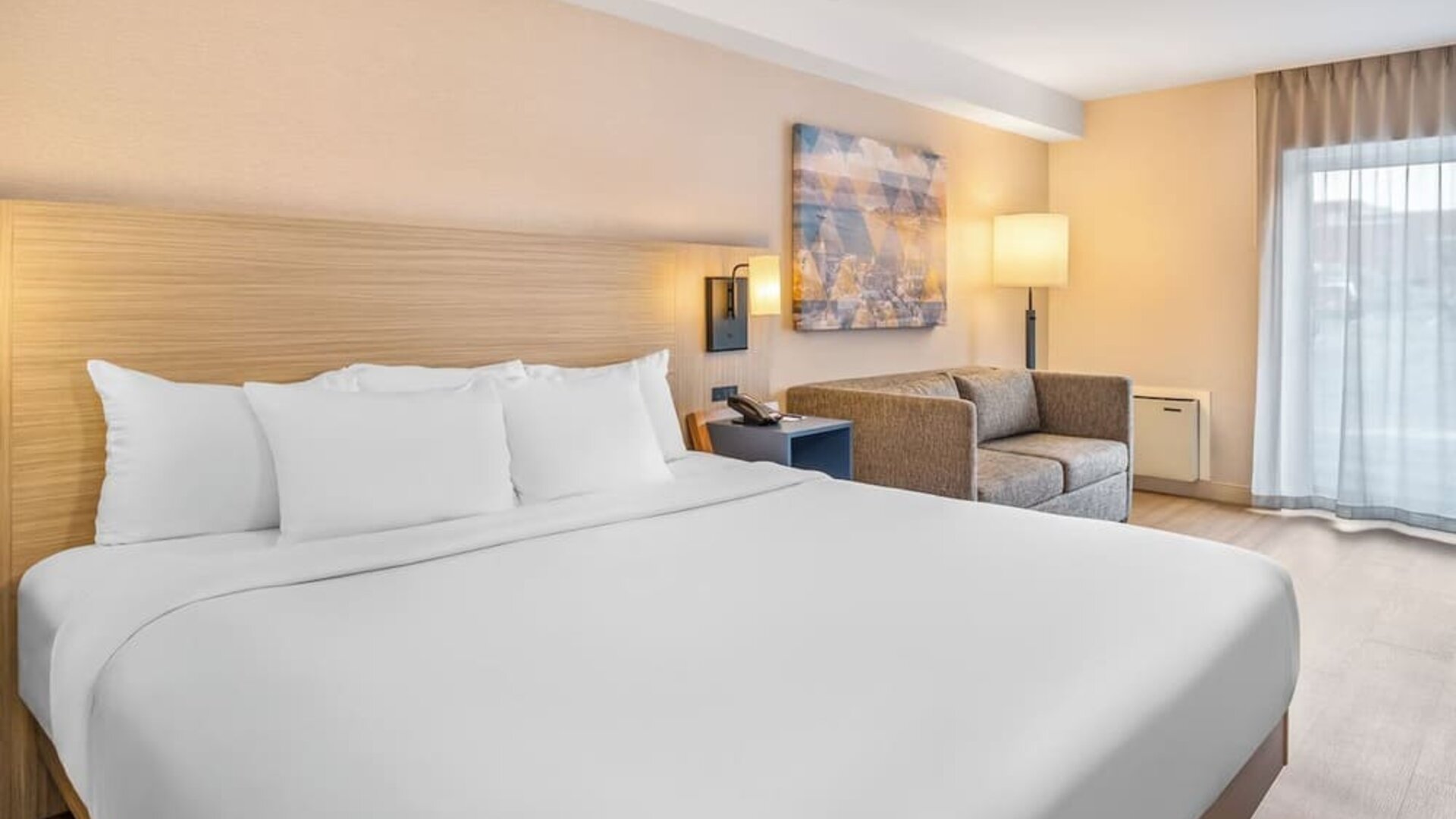 Spacious guest room featuring a plush king bed, comfortable seating area, and contemporary décor at Comfort Inn Airport East Ancienne-Lorette.