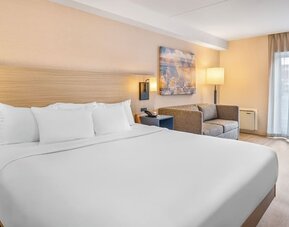 Spacious guest room featuring a plush king bed, comfortable seating area, and contemporary décor at Comfort Inn Airport East Ancienne-Lorette.