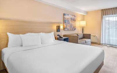 Spacious guest room featuring a plush king bed, comfortable seating area, and contemporary décor at Comfort Inn Airport East Ancienne-Lorette.