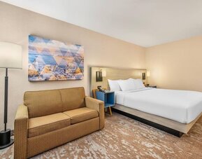 Comfortable day-use guest room with a king bed, sofa, and modern amenities, ideal for work or daytime relaxation at Comfort Inn Airport East Ancienne-Lorette.