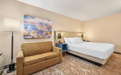 Comfortable day-use guest room with a king bed, sofa, and modern amenities, ideal for work or daytime relaxation at Comfort Inn Airport East Ancienne-Lorette.