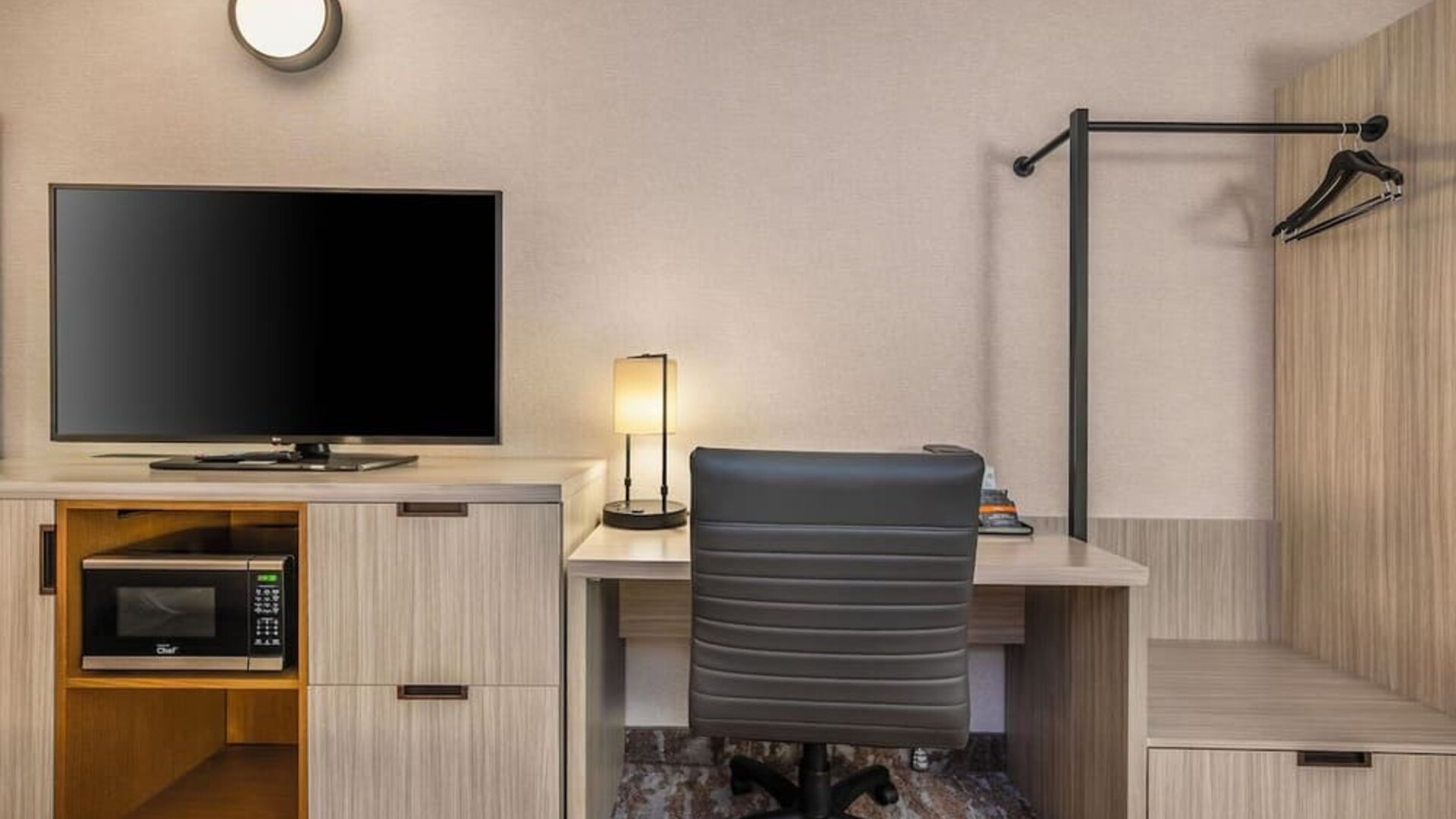 In-room workspace with a desk, flat-screen TV, microwave, and convenient storage at Comfort Inn Airport East Ancienne-Lorette.