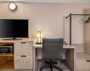 In-room workspace with a desk, flat-screen TV, microwave, and convenient storage at Comfort Inn Airport East Ancienne-Lorette.