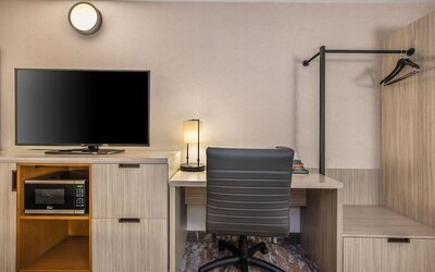 In-room workspace with a desk, flat-screen TV, microwave, and convenient storage at Comfort Inn Airport East Ancienne-Lorette.
