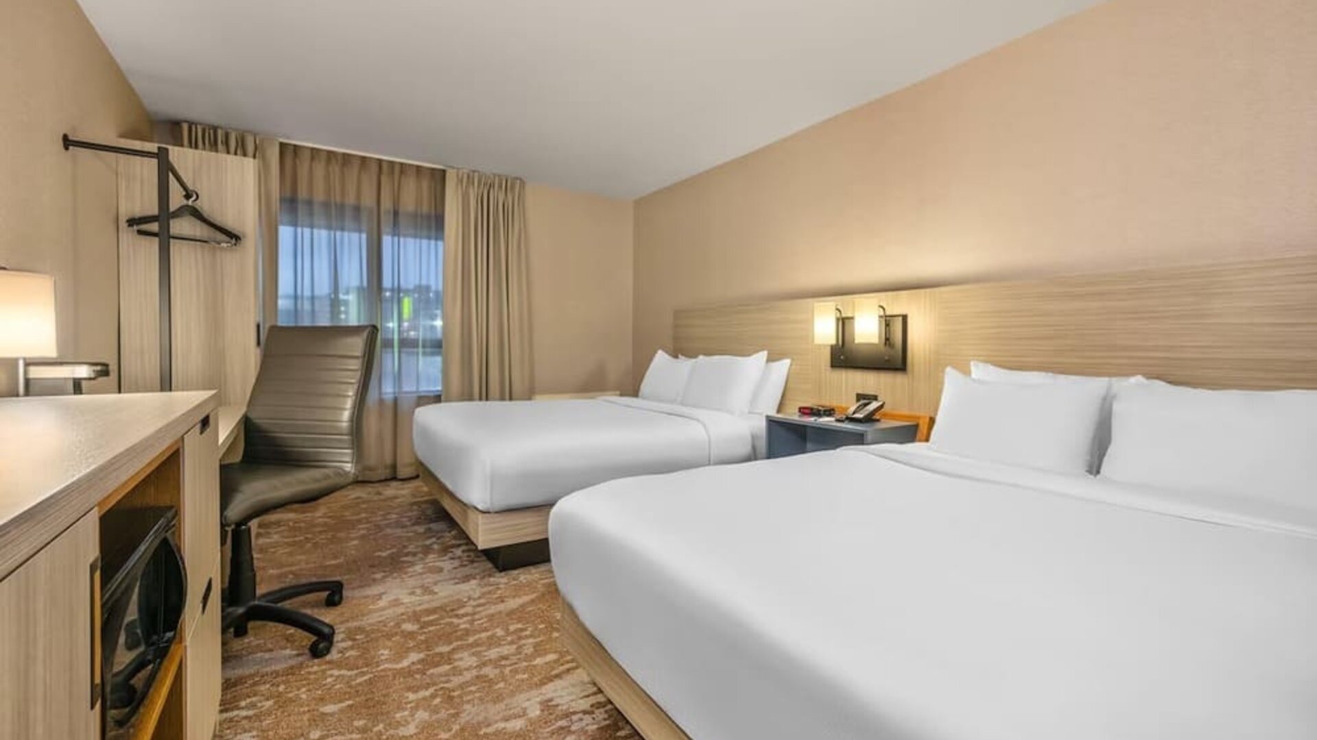 Guest room featuring two comfortable beds, a functional workspace, and modern amenities for a relaxing stay at Comfort Inn Airport East Ancienne-Lorette.