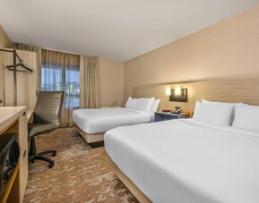 Guest room featuring two comfortable beds, a functional workspace, and modern amenities for a relaxing stay at Comfort Inn Airport East Ancienne-Lorette.