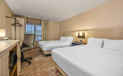 Guest room featuring two comfortable beds, a functional workspace, and modern amenities for a relaxing stay at Comfort Inn Airport East Ancienne-Lorette.