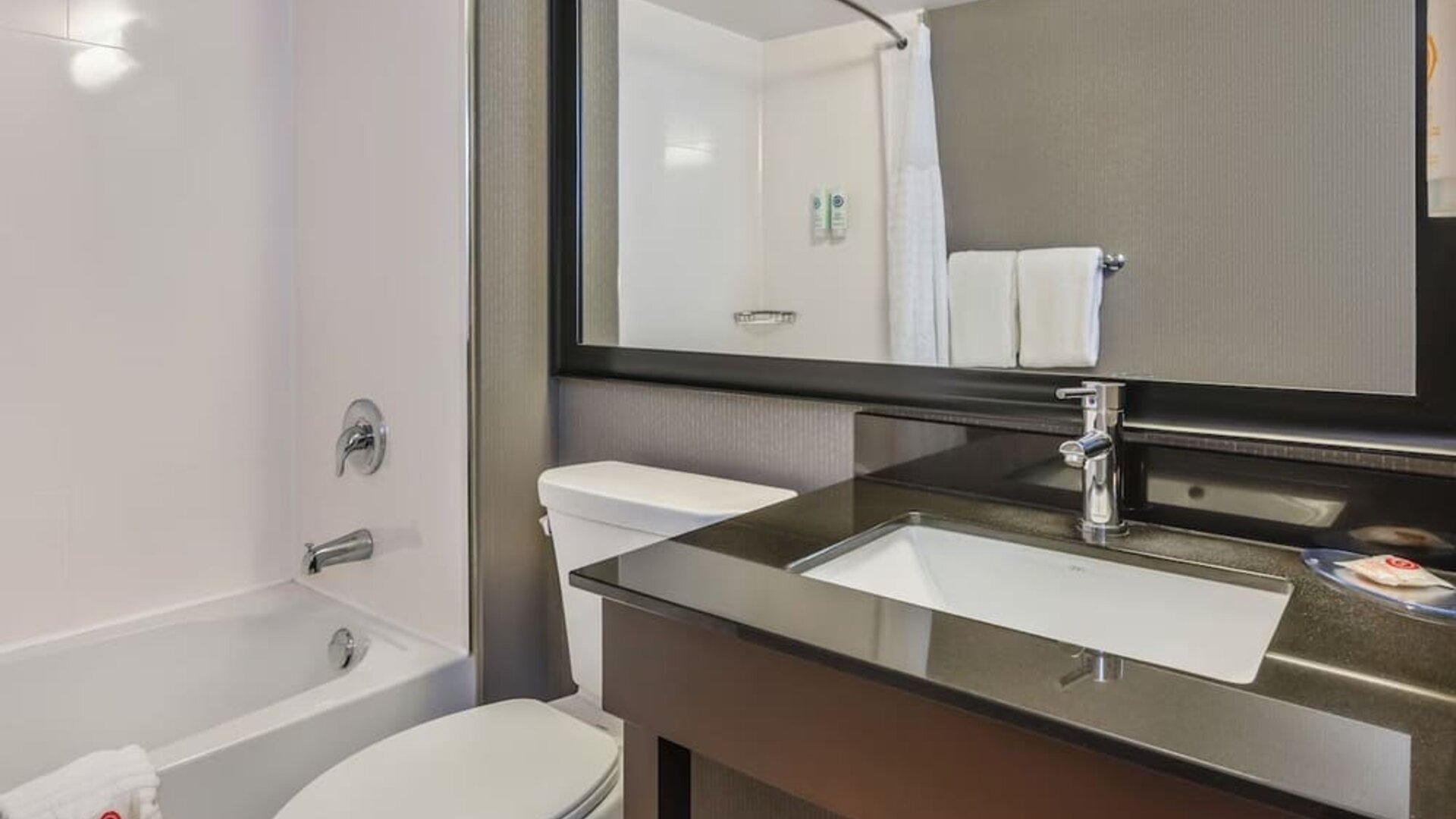 Modern guest bathroom featuring a bathtub and shower combination, contemporary vanity, and complimentary bath amenities at Comfort Inn Airport East Ancienne-Lorette.