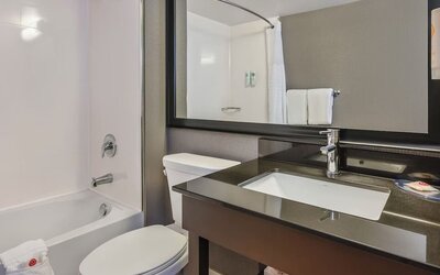 Modern guest bathroom featuring a bathtub and shower combination, contemporary vanity, and complimentary bath amenities at Comfort Inn Airport East Ancienne-Lorette.