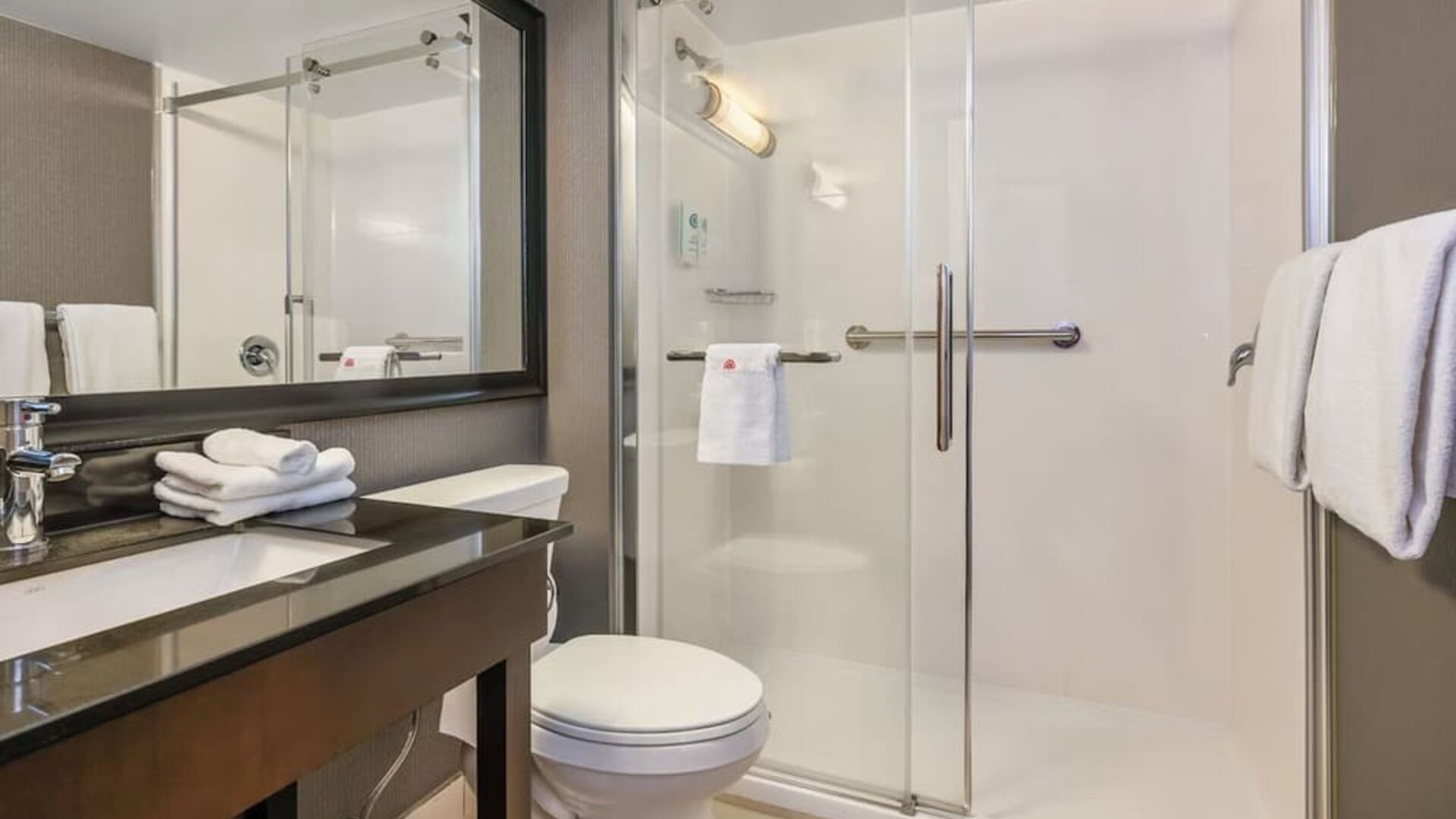 Accessible guest bathroom with a roll-in shower, grab bars, and mobility-friendly features at Comfort Inn Airport East Ancienne-Lorette.