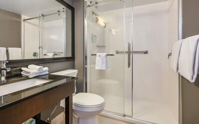 Accessible guest bathroom with a roll-in shower, grab bars, and mobility-friendly features at Comfort Inn Airport East Ancienne-Lorette.