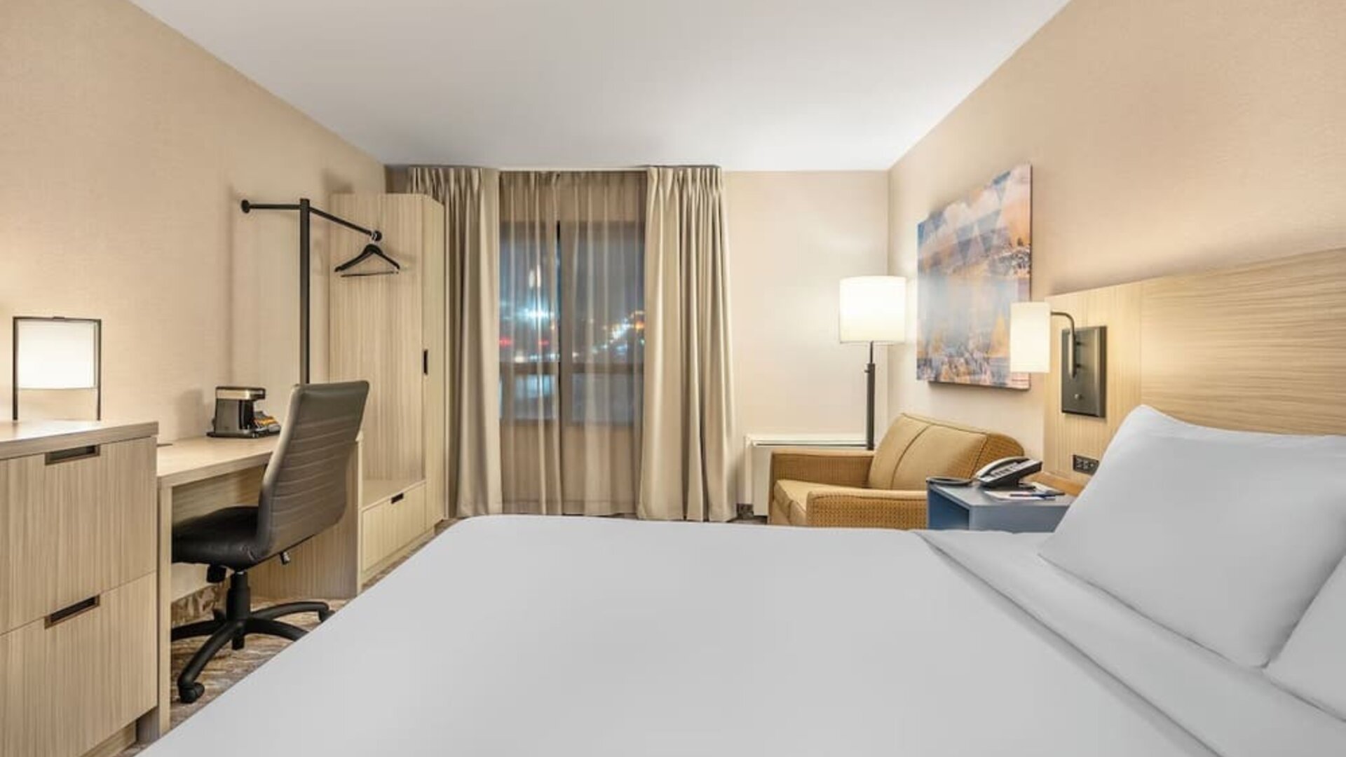 Guest room with a king bed, comfortable seating area, and large windows providing abundant natural light at Comfort Inn Airport East Ancienne-Lorette.