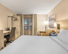 Guest room with a king bed, comfortable seating area, and large windows providing abundant natural light at Comfort Inn Airport East Ancienne-Lorette.