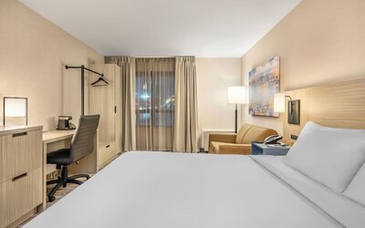 Guest room with a king bed, comfortable seating area, and large windows providing abundant natural light at Comfort Inn Airport East Ancienne-Lorette.