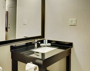 Modern bathroom vanity with granite countertop, large mirror, fresh towels, and complimentary toiletries at Comfort Inn Baie-Comeau.