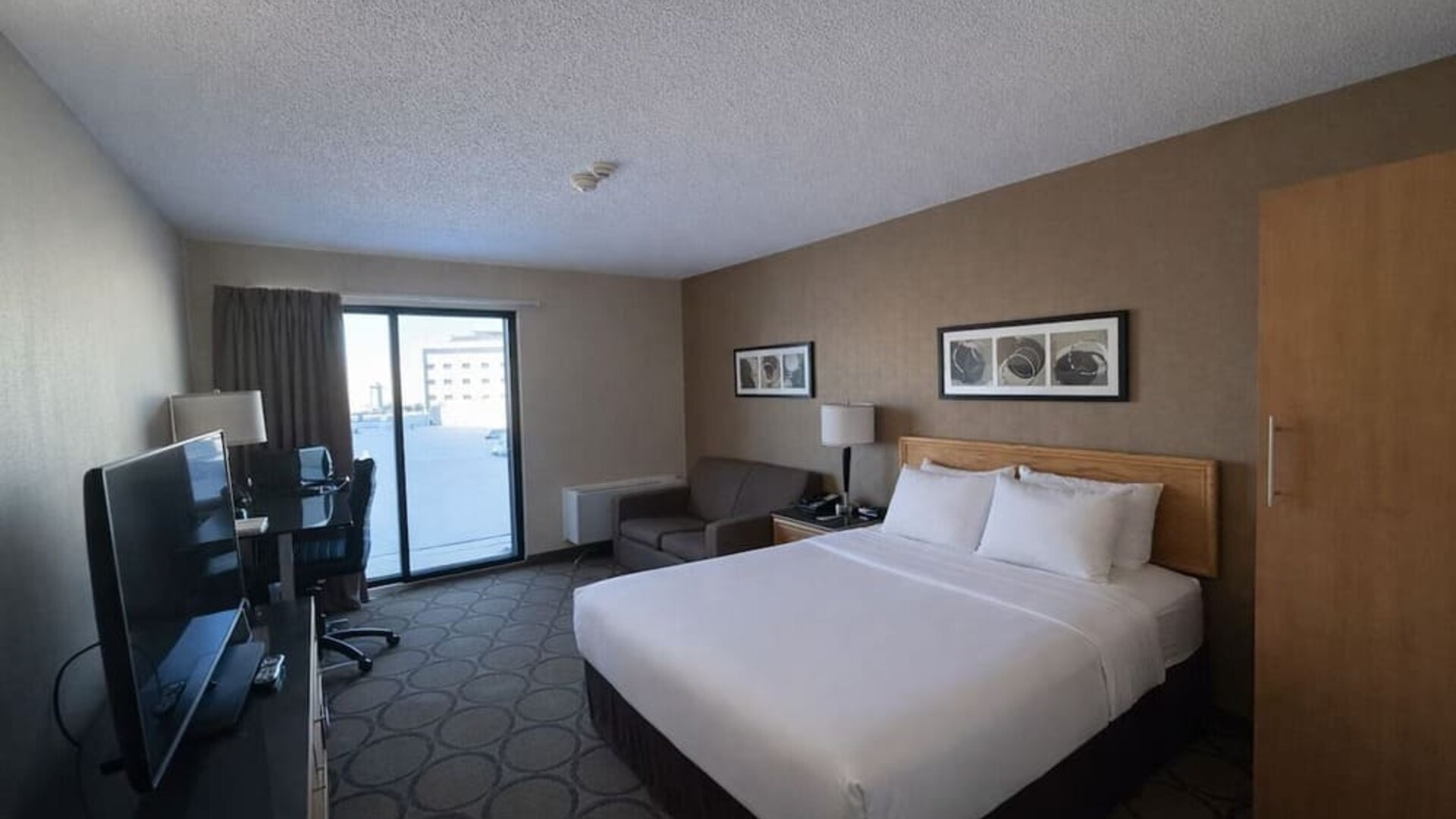 Comfortable king room with premium bedding, sofa, spacious work area, and flat-screen TV at Comfort Inn Baie-Comeau.